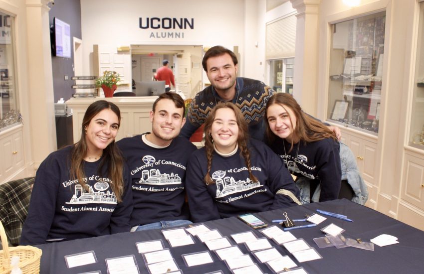 5 SAA students smile as they check in guests for an event at the Alumni Center