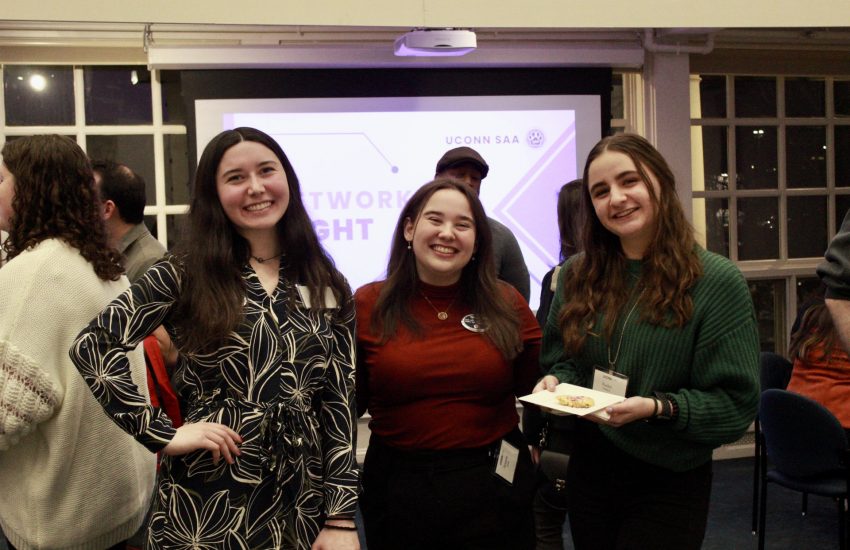 Three students smiling at a networking event